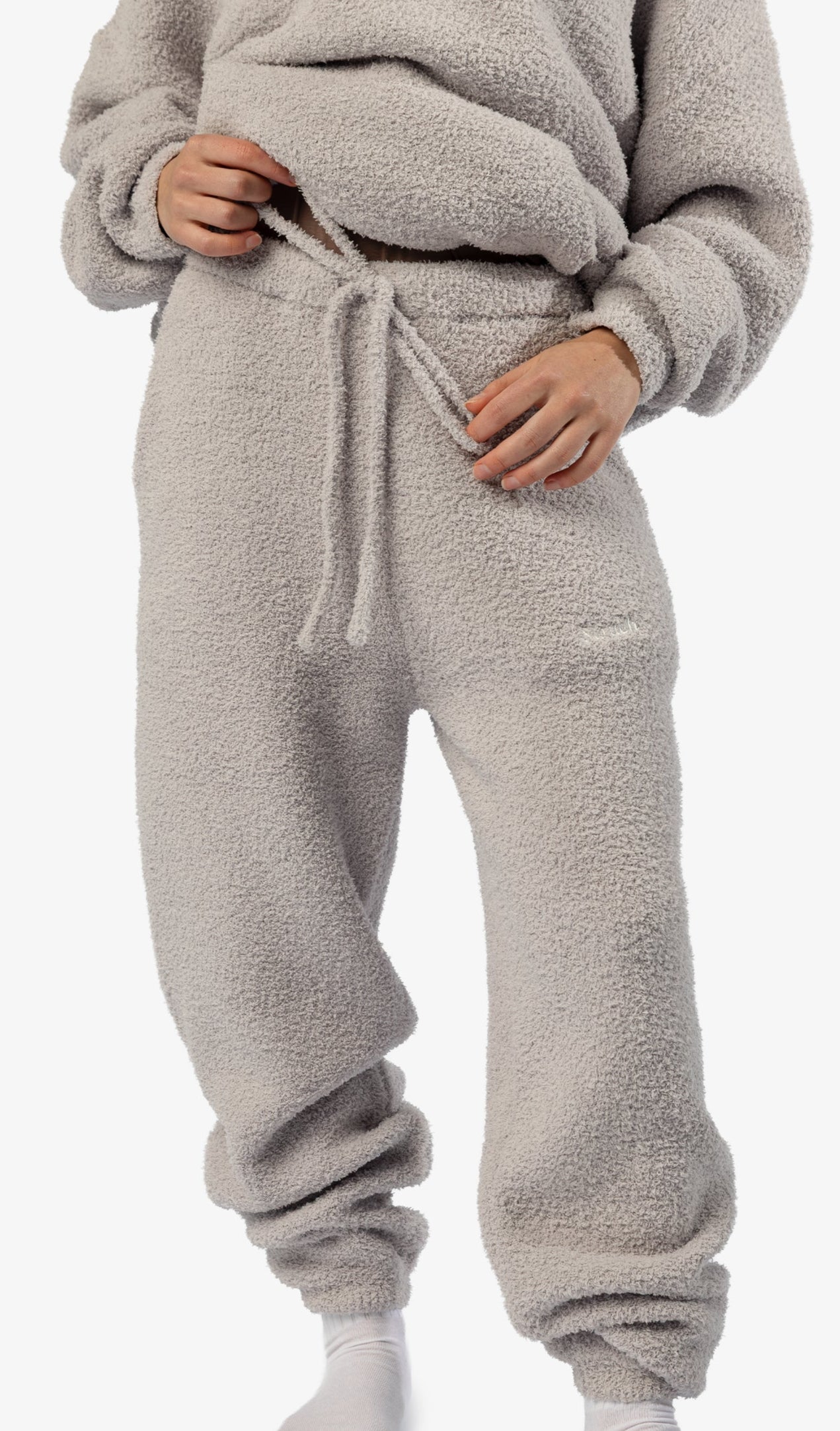 Person wearing a beige fleece tracksuit on a white background